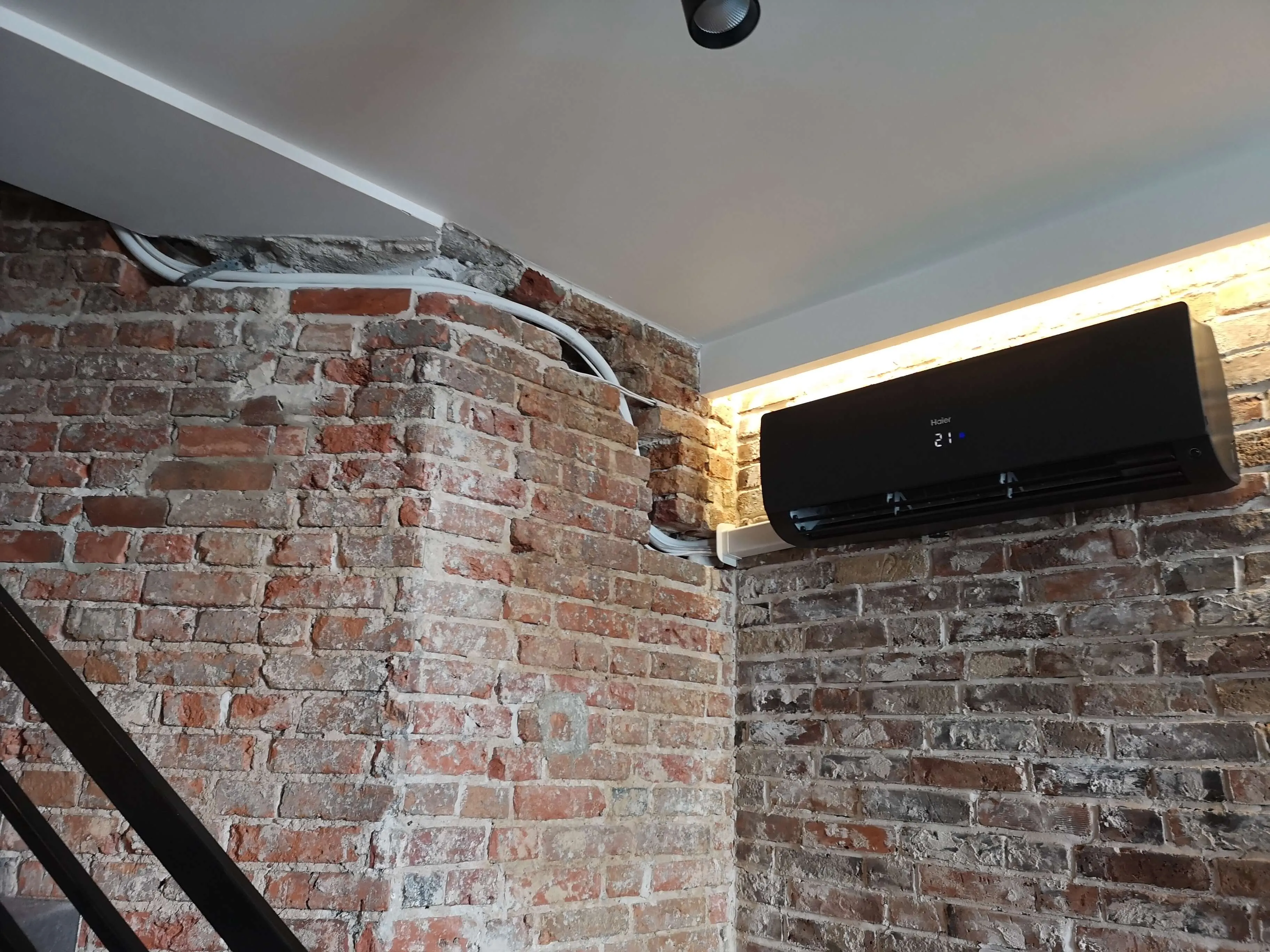 klimatyzator  czarny zamontowany na ceglanej ścianie